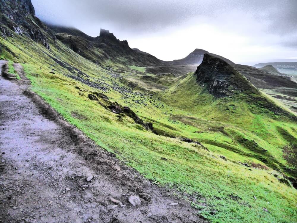 Matschiger Wanderweg neben grüner Landschaft